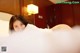 A woman laying on top of a bed covered in white sheets.