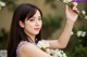 A woman holding a branch with white flowers in her hand.