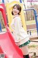 A young woman standing in front of a red slide.