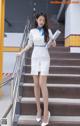 A woman in a white dress is standing on some stairs.