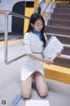 A woman in a white dress is sitting on the stairs.