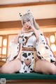 A woman in a cow costume sitting on a bed.