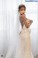 A woman in a wedding dress with a tattoo on her arm.