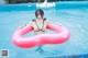 A woman in a bikini floating on an inflatable ring in a pool.