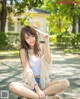 A woman sitting on the ground wearing a straw hat.