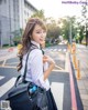 A woman in a school uniform is standing on the street.