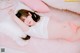 A woman laying on top of a pink bed next to pillows.