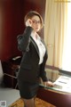 A woman in a business suit and glasses posing for a picture.