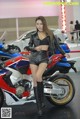 A woman standing next to a motorcycle on display.