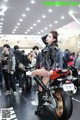 A woman sitting on a motorcycle in a showroom.