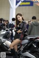 A woman sitting on top of a motorcycle in a showroom.