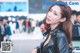 A woman in a black leather jacket standing next to a car.