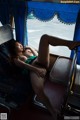 A naked woman sitting on a bus with her legs up.