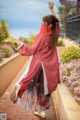 A woman in a red kimono is dancing on a brick walkway.