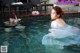 A woman in a white dress is taking a picture of herself in a pool.