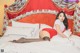 A woman in a red and white outfit laying on a bed.